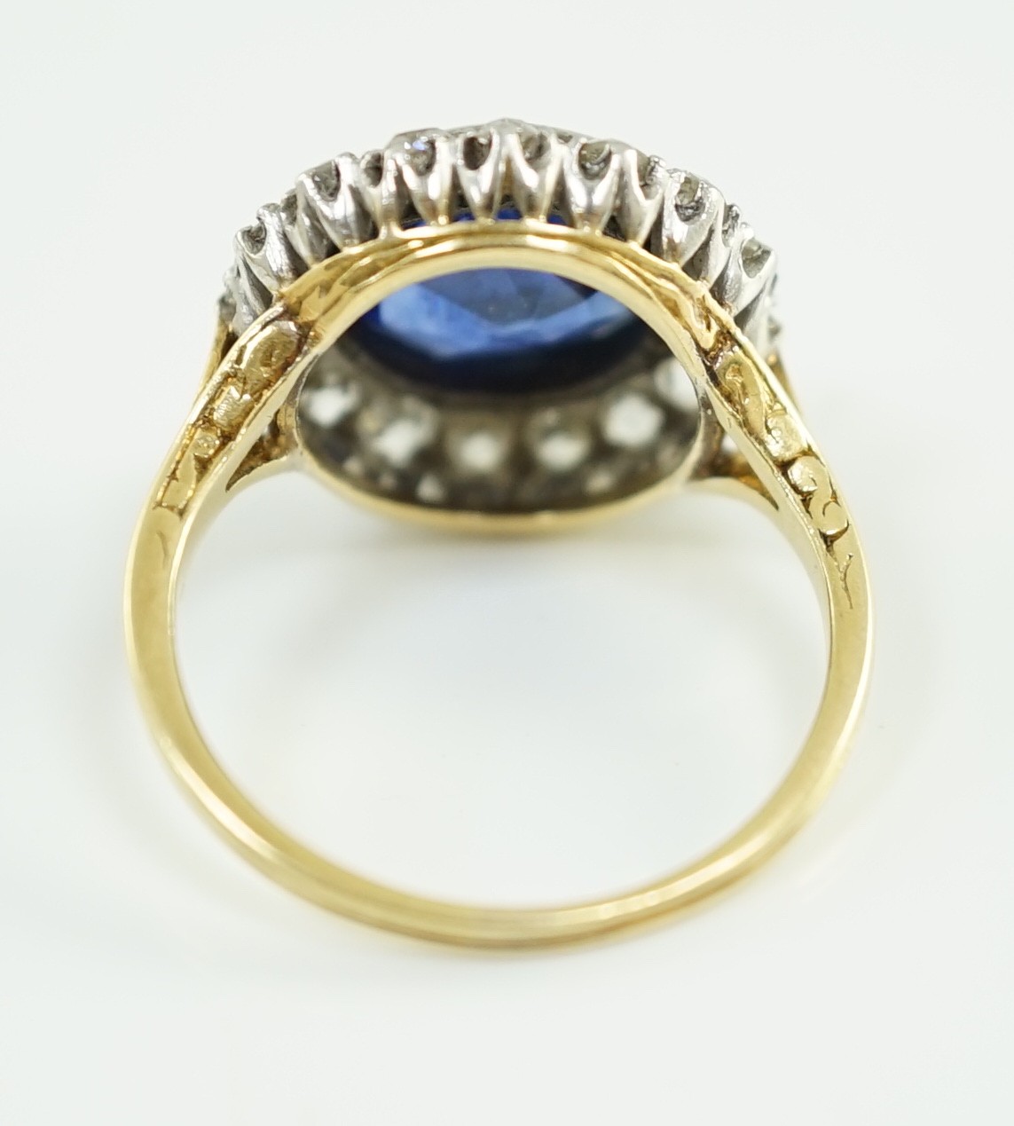 A gold and single stone round cut sapphire set dress ring, with diamond set border